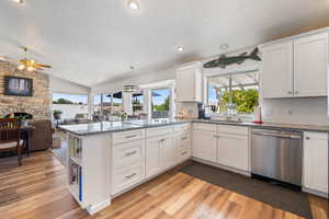 Kitchen featuring a textured ceiling, light wood-style floors, healthy amount of natural light, a peninsula, and lofted ceiling