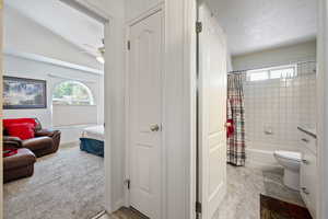 Full bath featuring connected bathroom, a textured ceiling, shower / bath combo, a ceiling fan, and vaulted ceiling