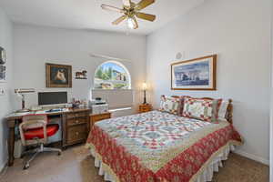 Bedroom featuring light colored carpet, an office area, and a ceiling fan