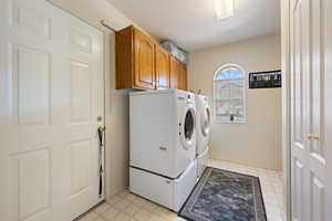 Washroom featuring washing machine and dryer, cabinet space, and a textured ceiling