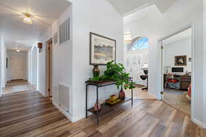 Hallway featuring wood finished floors, a desk, arched walkways, and a chandelier