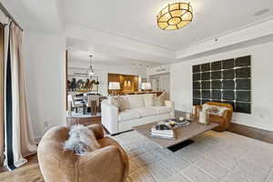 Living room featuring wood finished floors, a raised ceiling, and crown molding