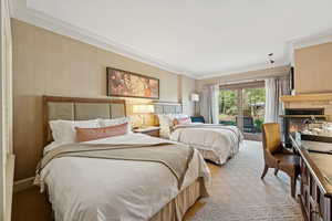 Bedroom featuring access to outside, crown molding, light carpet, and a glass covered fireplace
