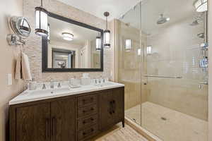 Full bath featuring a shower stall and double vanity