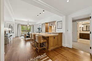 Kitchen featuring dark wood-style flooring, light stone counters, a breakfast bar area, backsplash, and recessed lighting