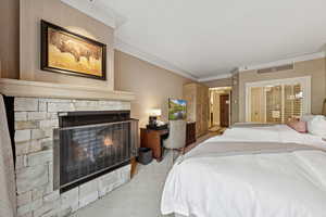 Carpeted bedroom featuring a fireplace and crown molding
