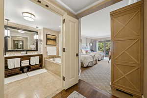 Ensuite bathroom featuring a bath, vanity, and crown molding