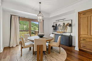 Dining area featuring a chandelier, dark wood-style flooring, and ornamental molding