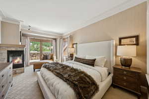 Bedroom featuring ornamental molding and a stone fireplace