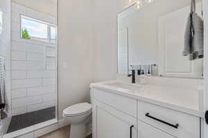 Full bathroom with vanity, tiled shower, and wood finished floors