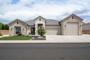 View of front of home featuring a garage, stone siding, concrete driveway, a tile roof, and stucco siding