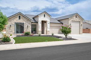 View of front of property with stone siding, a front lawn, and a garage