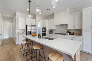 Kitchen featuring a breakfast bar, backsplash, appliances with stainless steel finishes, light wood-style flooring, and recessed lighting