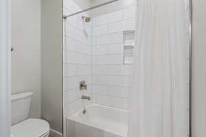 Full bath with shower / bath combo with shower curtain and toilet