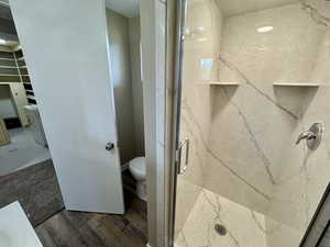 Full bath with a marble finish shower and toilet