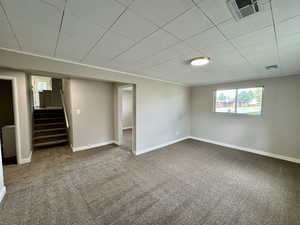 Carpeted empty room featuring baseboards and stairway