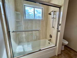 Full bathroom featuring bath / shower combo with glass door and tile patterned floors
