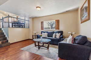 Living area featuring wood finished floors, a textured ceiling, and stairs