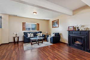 Living area with wood finished floors and a warm lit fireplace