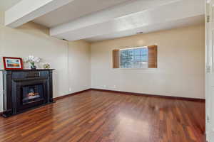 Unfurnished living room featuring wood finished floors and a lit fireplace