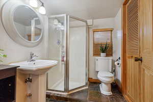 Full bath featuring stone tile flooring, a shower stall, and a closet