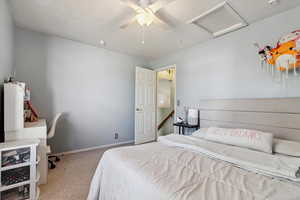 Bedroom featuring carpet flooring, attic access, and ceiling fan