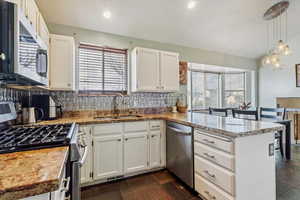 Kitchen with stainless steel appliances, a peninsula, backsplash, plenty of natural light, and recessed lighting