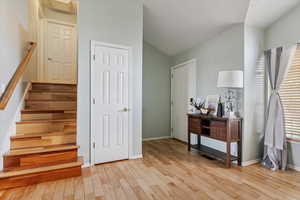 Stairway with wood finished floors and vaulted ceiling