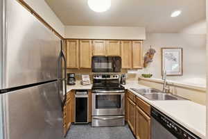 Kitchen featuring appliances with stainless steel finishes, light countertops, light brown cabinets, and recessed lighting