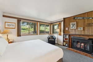 Bedroom with wood walls, carpet flooring, and a fireplace with flush hearth
