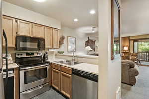 Kitchen featuring stainless steel appliances, carpet, light countertops, recessed lighting, and light brown cabinetry