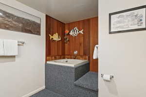Full bath featuring a bath and wood walls