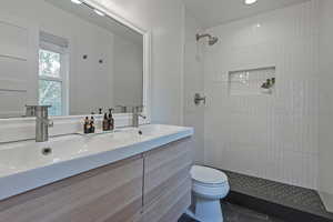 Full bath featuring double vanity, a tile shower, and tile patterned flooring