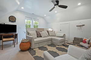 Living room with vaulted ceiling, a ceiling fan, light colored carpet, and recessed lighting