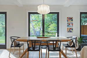 Dining space featuring light wood-style flooring, healthy amount of natural light, and beam ceiling