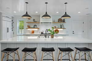 Kitchen featuring open shelves, light countertops, a spacious island, paneled built in fridge, and recessed lighting