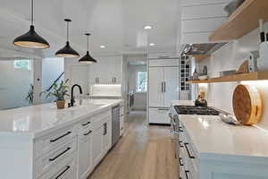 Kitchen featuring open shelves, light wood finished floors, recessed lighting, high end appliances, and white cabinetry