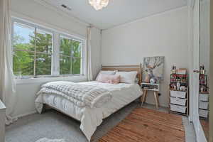 Bedroom with ornamental molding and carpet