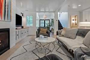 Living room with light wood-style flooring, stairs, a chandelier, and recessed lighting