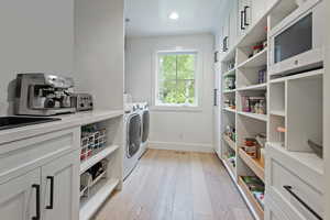 Laundry area with washer and dryer, light wood finished floors, and recessed lighting
