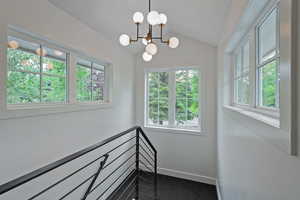 Stairway featuring a chandelier, vaulted ceiling, and carpet floors