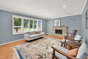 Living room featuring wood finished floors, recessed lighting, and a stone fireplace