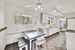 Kitchen with white appliances, a ceiling fan, white cabinets, light tile patterned floors, and track lighting