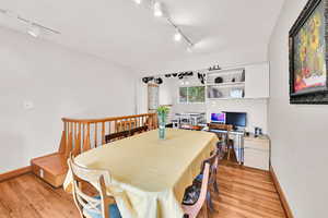 Dining area with track lighting, light wood-style floors, and a desk