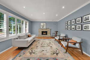 Living room featuring wood finished floors, recessed lighting, a fireplace, and ornamental molding