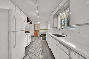 Kitchen with white appliances, light tile patterned floors, white cabinetry, and light countertops
