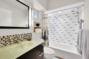Full bathroom with tasteful backsplash, vanity, and shower / tub combo with curtain