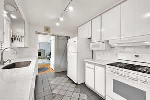Kitchen with white appliances, white cabinetry, ventilation hood, and light tile patterned floors