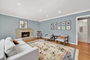 Living room featuring recessed lighting, wood finished floors, a fireplace, and crown molding