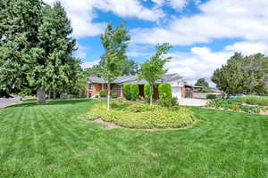 View of grassy yard featuring a garage and driveway